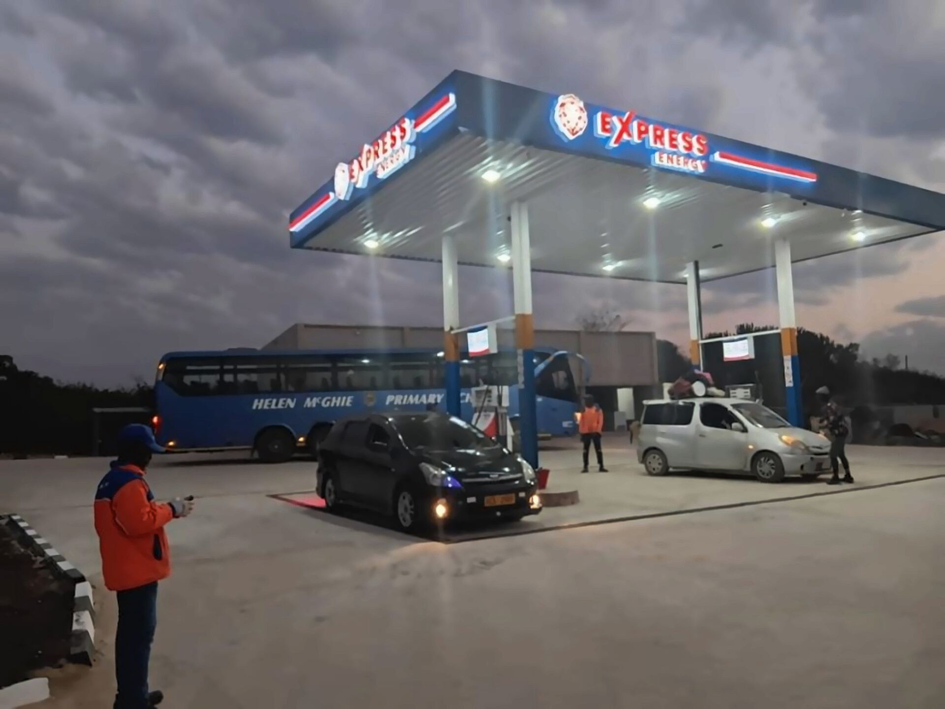 Express Energy station at dusk — Helen McGhie Primary School bus and family car at the pumps