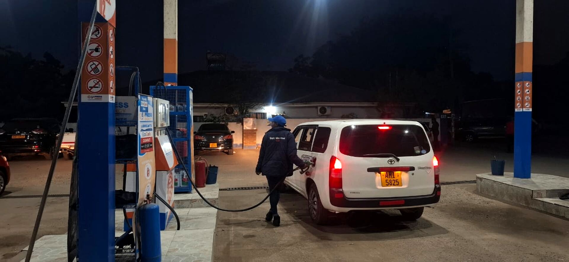 Express Energy attendant in branded jacket fueling a Toyota at night